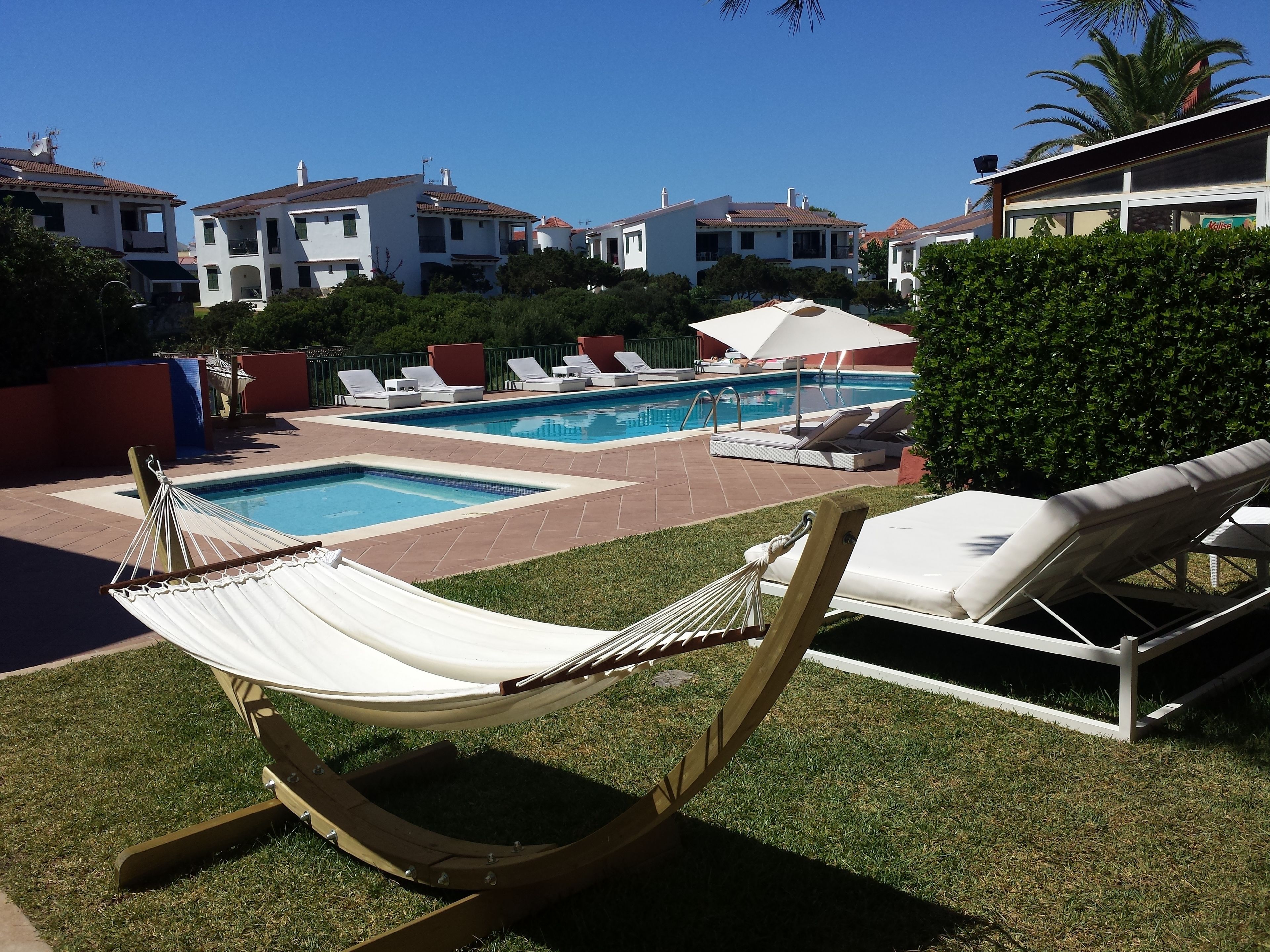 Ein Poolbereich mit Liegestühlen und einer Hängematte.