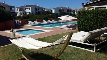 Un área de piscina con sillones de descanso y una hamaca.