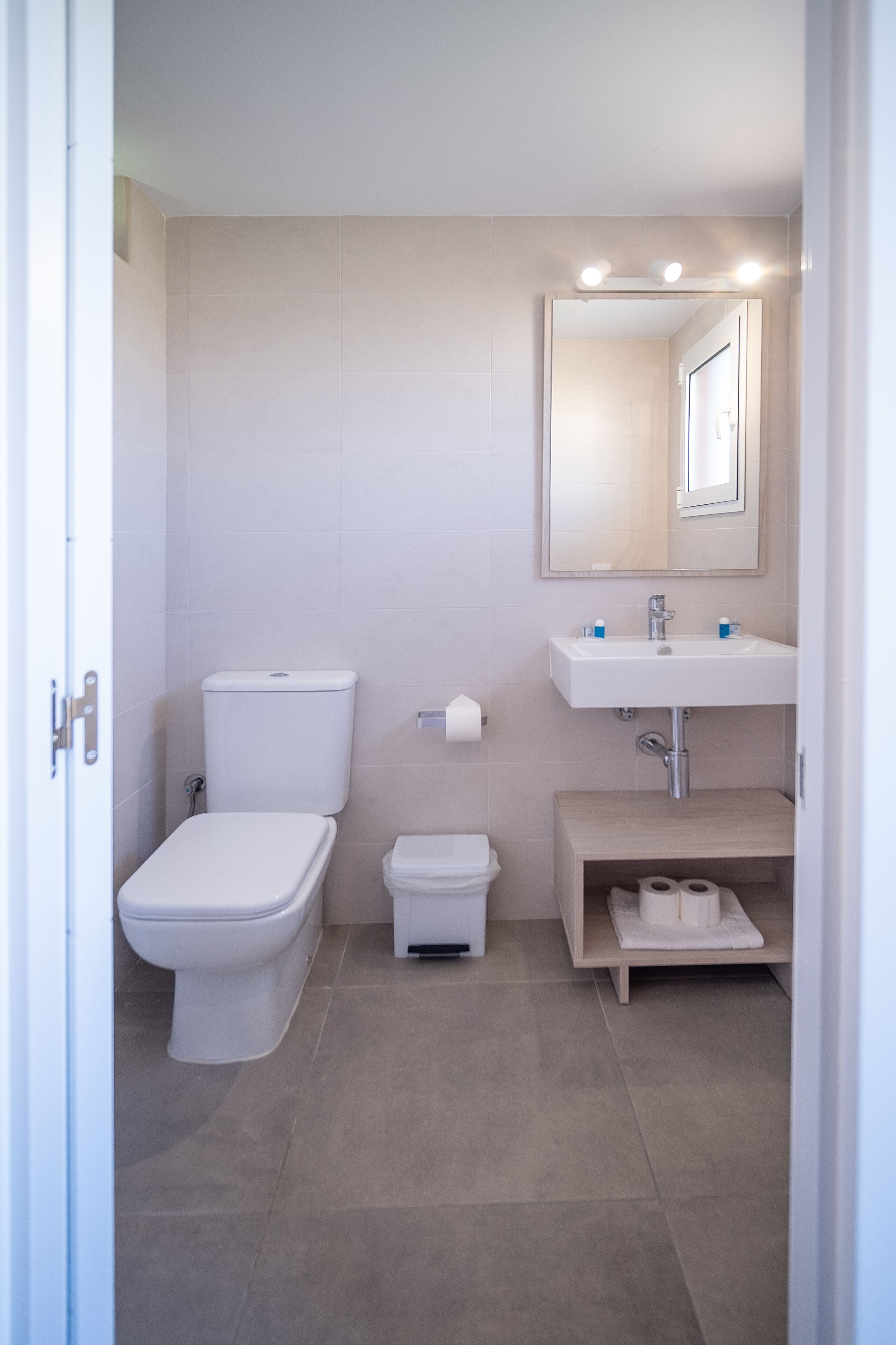 Een moderne badkamer met toilet, wastafel en spiegel.