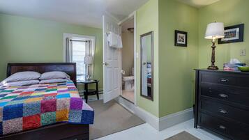 A bedroom with a bed, dresser, and a door leading to a bathroom.