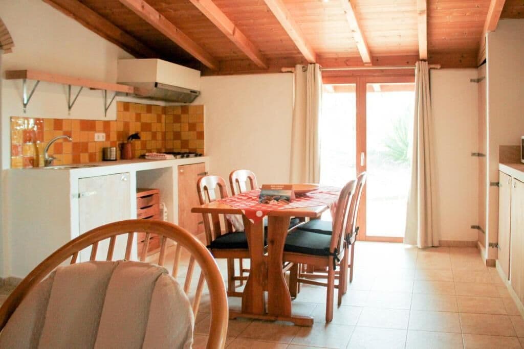 A cozy kitchen with wooden furniture, a tiled backsplash, and a dining area with chairs and a table.