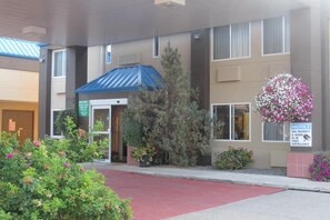 A hotel entrance with a blue awning, a notice sign, and a red carpet. - Rocky Inn Express (Rocky Mountain House)