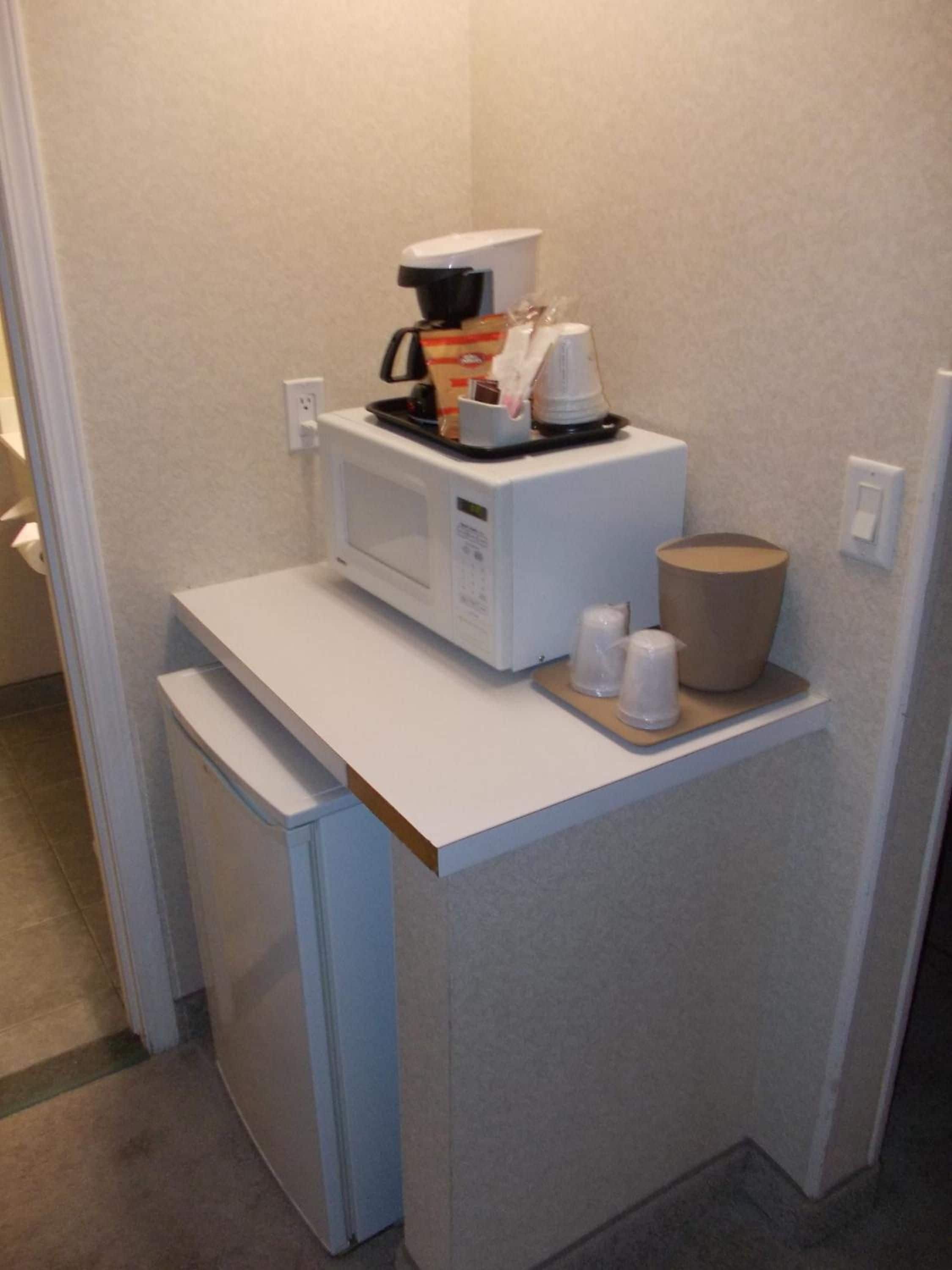 A compact kitchenette with a microwave, coffee maker, and a small refrigerator.