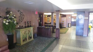 Un hall de hotel con una recepción, un arreglo floral grande y una alfombra estampada.