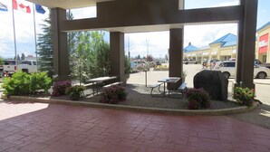 Un espacio al aire libre techado con asientos, una parrilla y plantas en macetas.