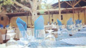 A dining area with tables set for a meal, featuring clear glassware and blue napkins. - L'Auberge des Glycines (Hyères)