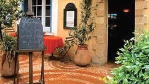 A courtyard with a chalkboard, potted plants, and a tiled floor. - L'Auberge des Glycines (Hyères)