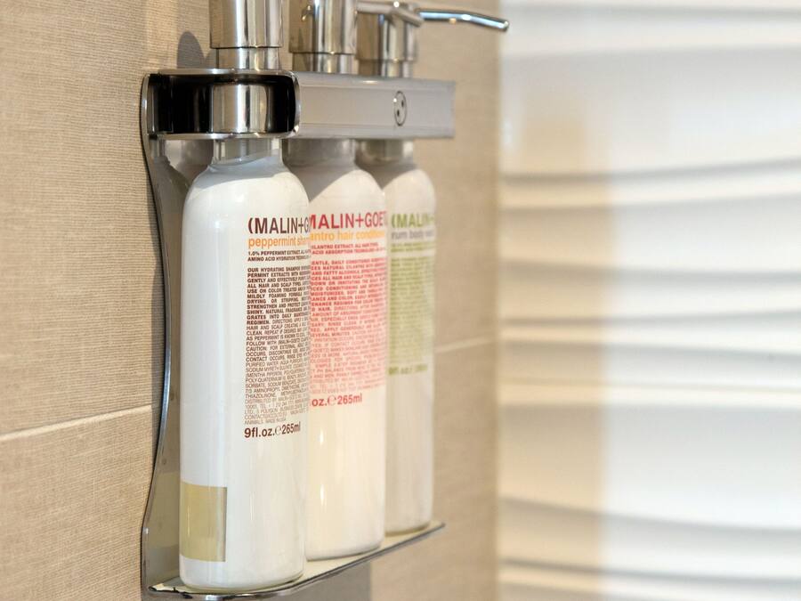 A bathroom shelf with three bottles of hair care products.