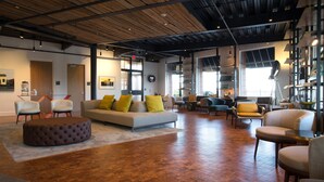 A spacious lobby with a wooden floor, a grey sofa with yellow cushions, and several chairs. - 250 Main Hotel (Rockland)