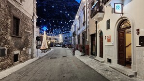 Une rue étroite bordée de bâtiments des deux côtés, un sapin de Noël et des guirlandes lumineuses.