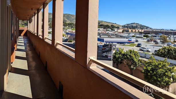 A corridor with a view of a parking lot and distant hills. - Royal Inn (South San Francisco)