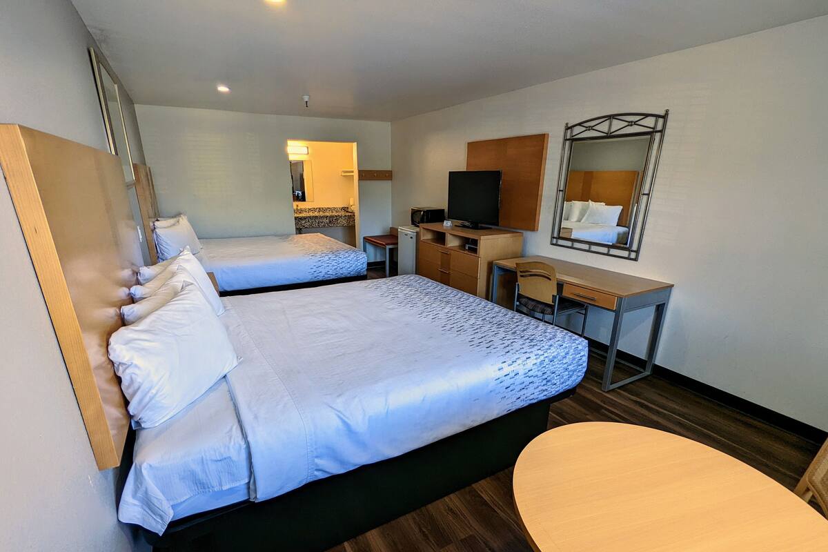 Une chambre d’hôtel avec deux lits, un bureau, une télévision et un miroir.