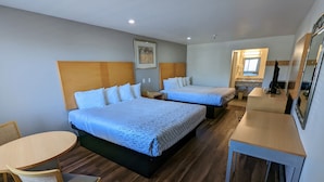 A hotel room with two beds, a desk, a chair, and a small table. - Royal Inn (South San Francisco)