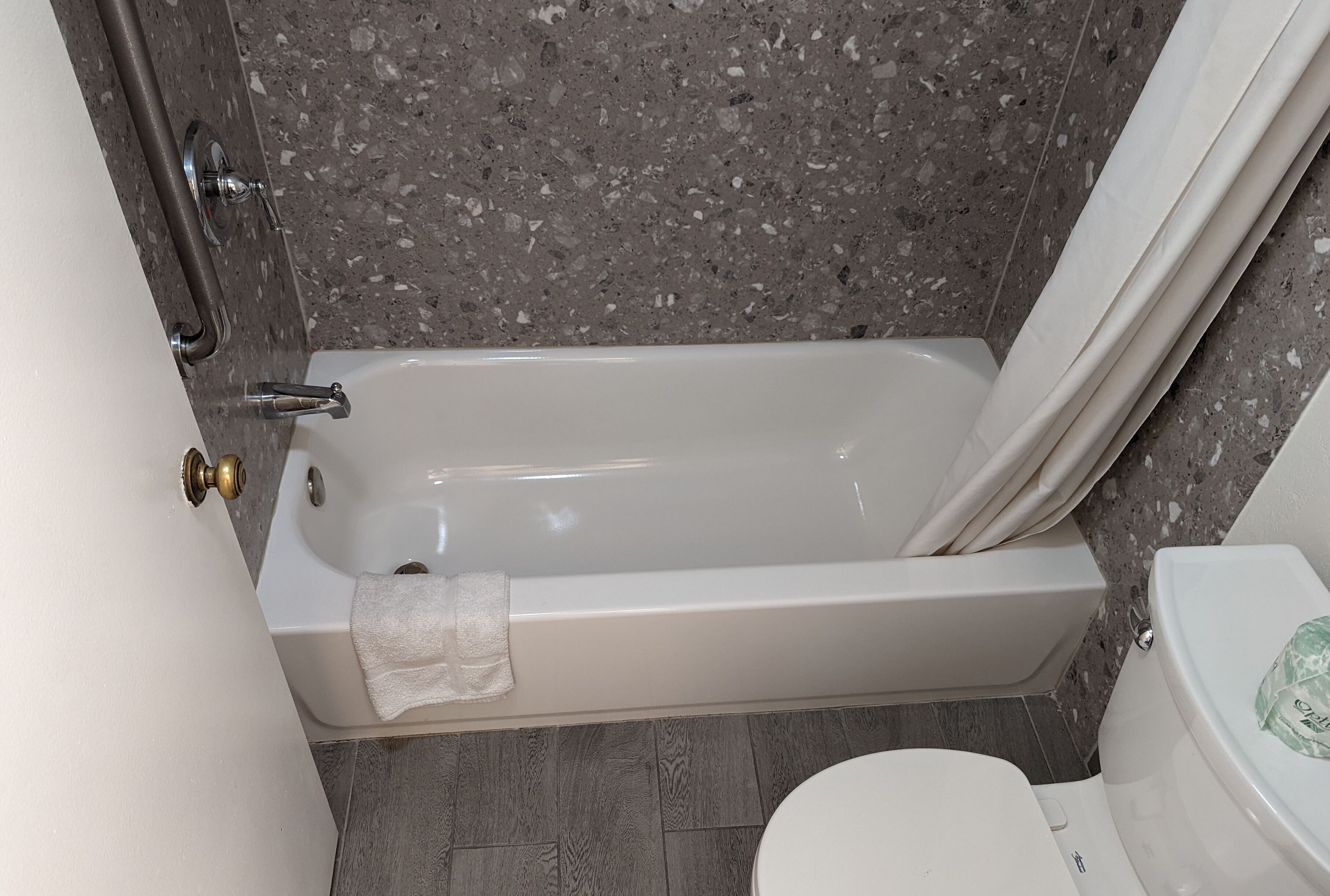 A bathroom with a bathtub, toilet, and a shower curtain.