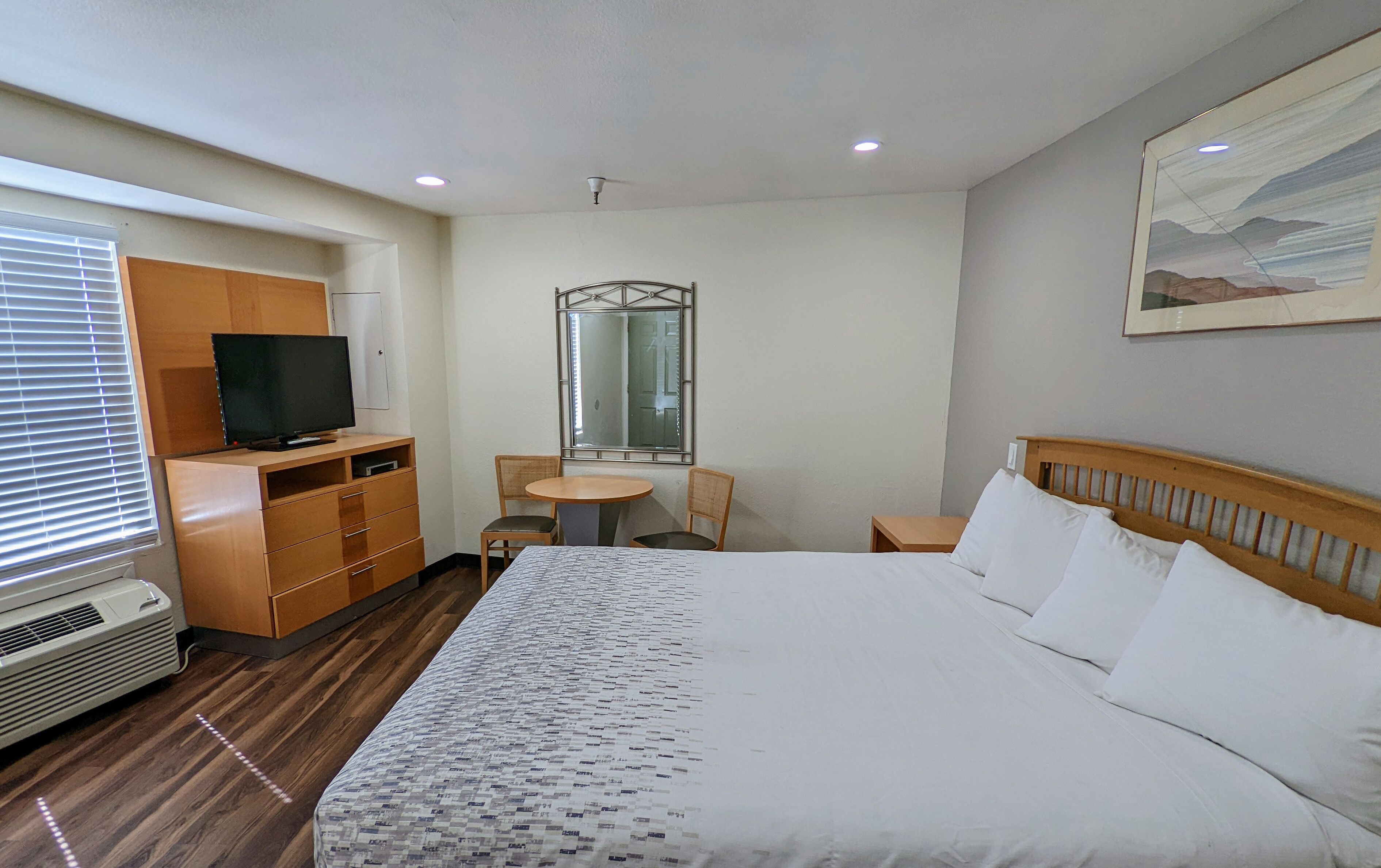 Habitación de hotel con cama, televisión, escritorio, silla y una mesita.