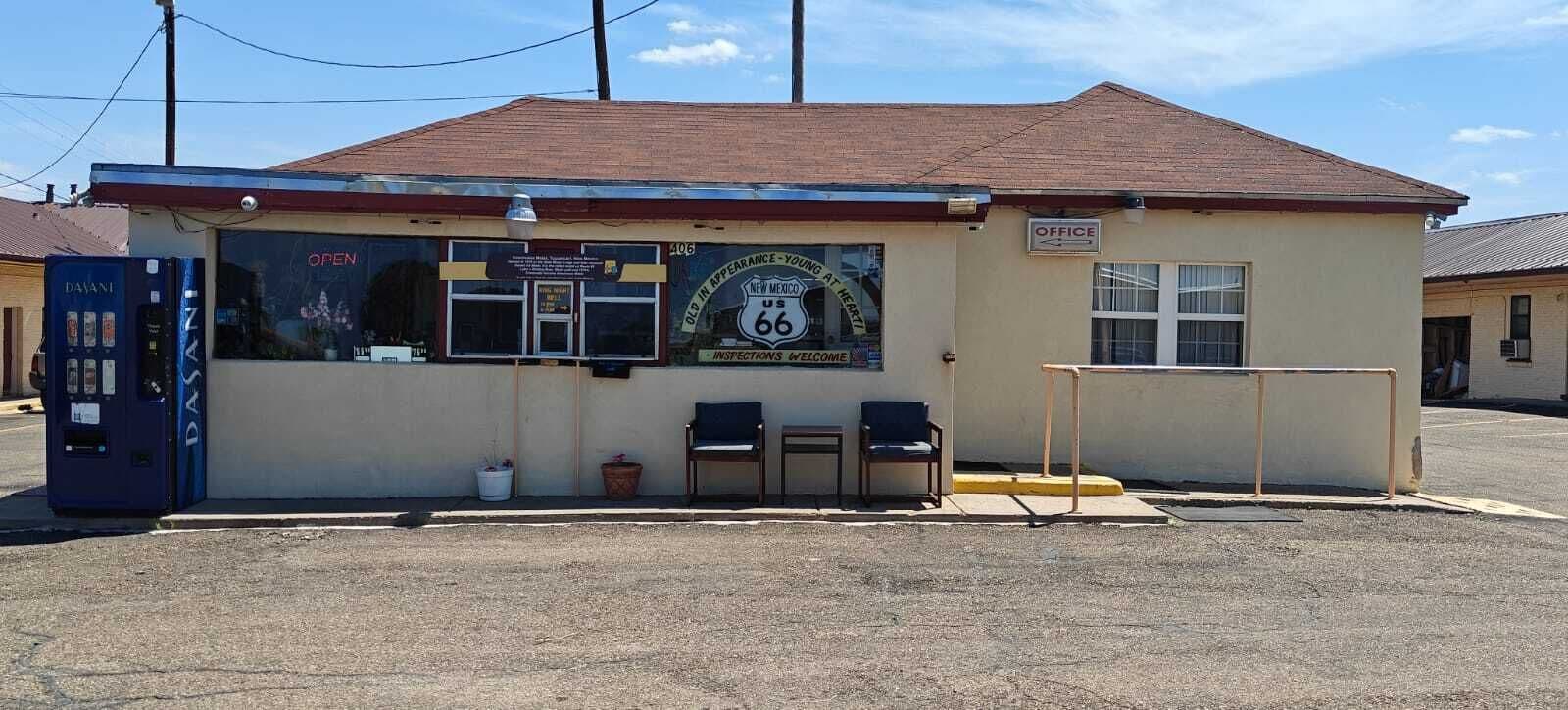 A small building with a sign indicating it is an office, a bench outside, and a mailbox.