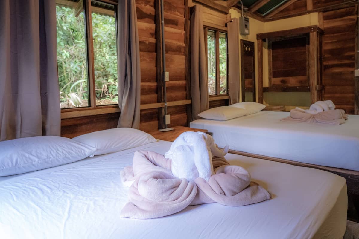 A wooden cabin with two beds, each with white linens and towels.