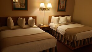 Een hotelkamer met twee bedden, een nachtkastje met een telefoon en twee wandlampen.