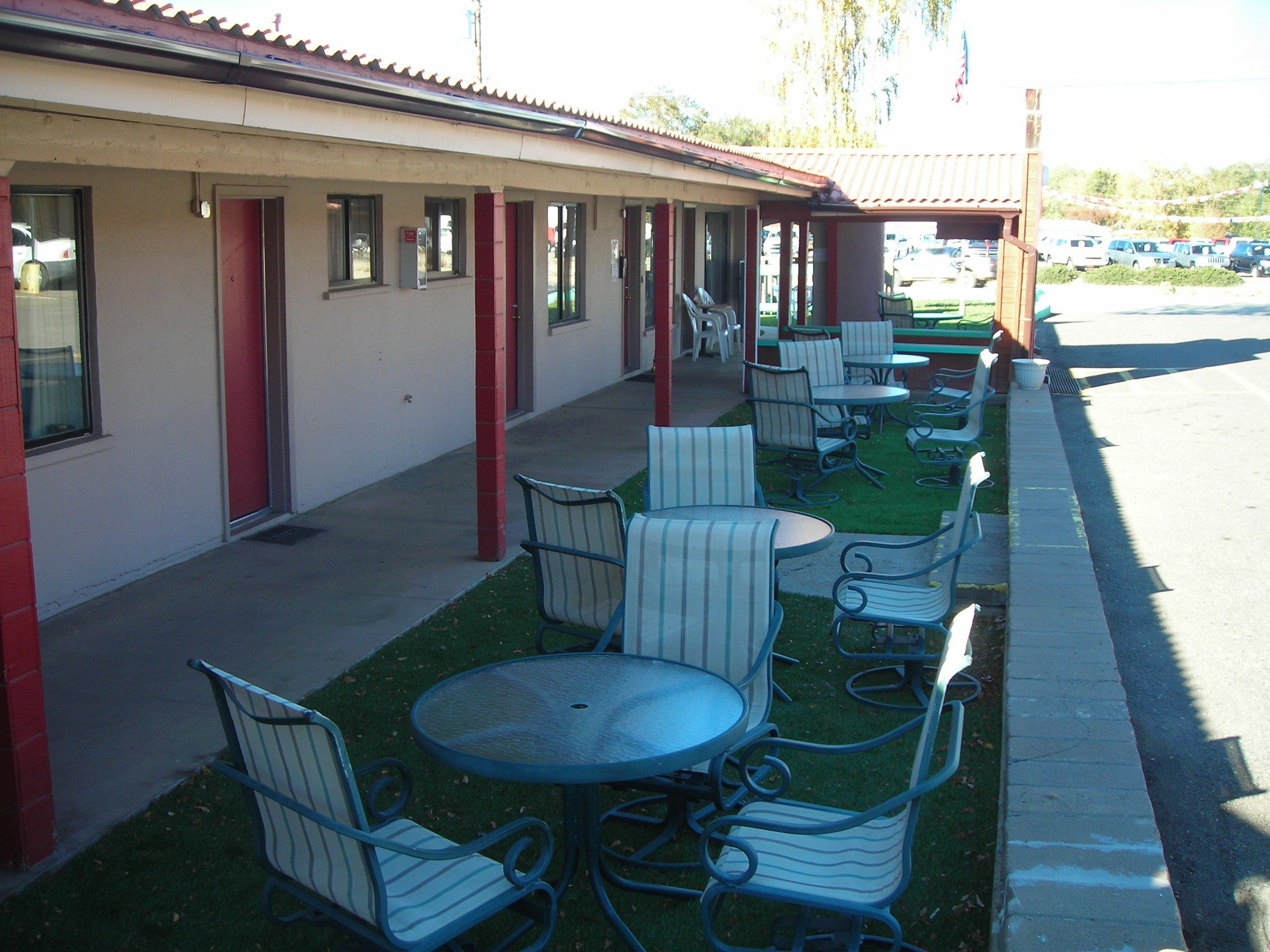 Un motel con área de asientos exteriores y un patio cubierto.