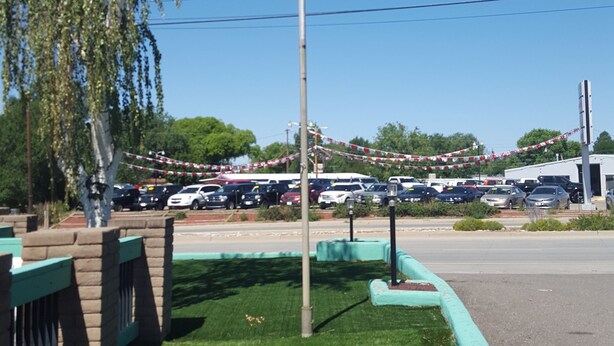 Een vlaggenmast met een Amerikaanse vlag, een parkeerplaats en een gazon met een bakstenen rand.