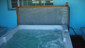 Een hottub met een houten hoofdsteun en bedieningspaneel.