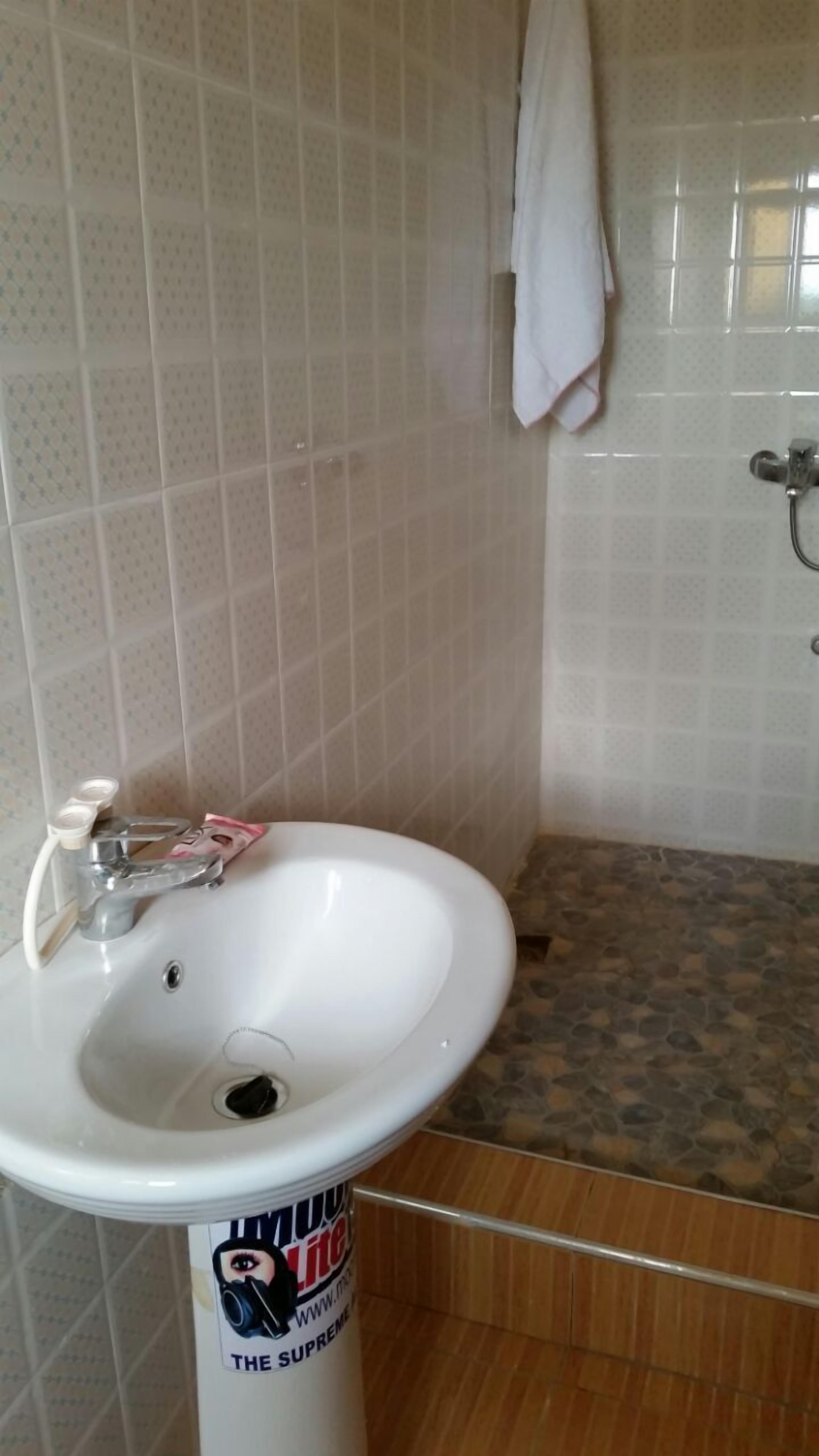 A bathroom with a white sink, a towel hanging on the wall, and a shower area.