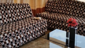 Una sala de estar con sofás estampados, una mesa de centro de vidrio y vistas a través de un ventanal.