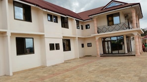 A multi-story building with a central entrance, large windows, and a balcony with railings. - Moonlite Hotel Sunyani Airport (Sunyani)