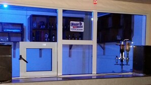 Zona de bar con un letrero del Hotel Moon, una grifería de cerveza y estantes con botellas. Hay sillas en primer plano.