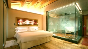 A modern bedroom with a large bed, a glass partition with a map design, and a wooden ceiling. - Can Bonastre Wine Resort, The Originals Relais (Relais du Silence) (Masquefa)