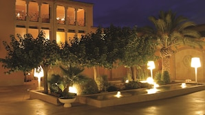 A courtyard with a pool, palm trees, and a building with arched windows. - Can Bonastre Wine Resort, The Originals Relais (Relais du Silence) (Masquefa)