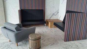 Una sala moderna con un sofá gris, una mesa de centro de madera y asientos tapizados a rayas.