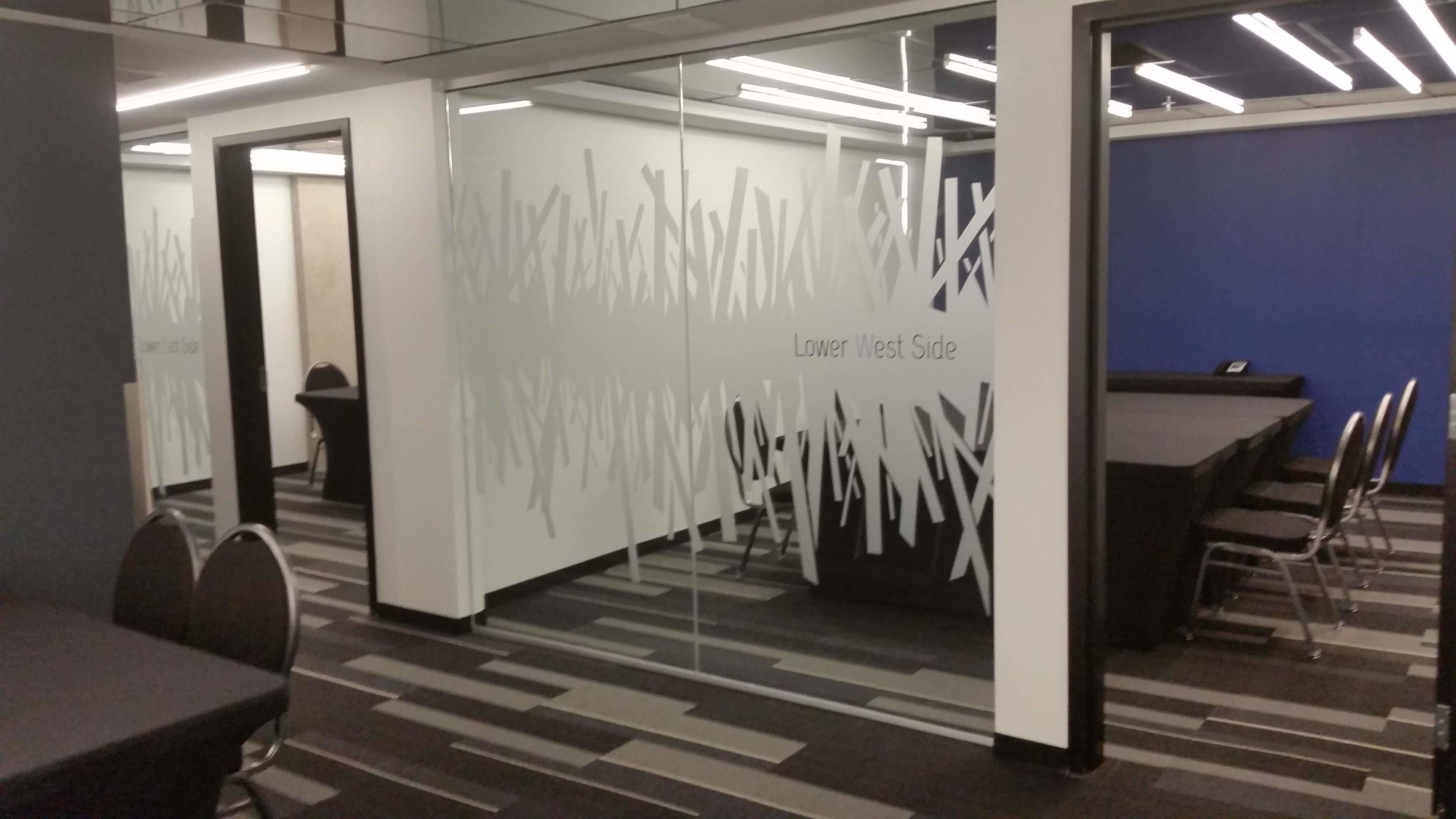 An office space with a modern design, featuring a patterned carpet, glass partitions, and a blue accent wall.