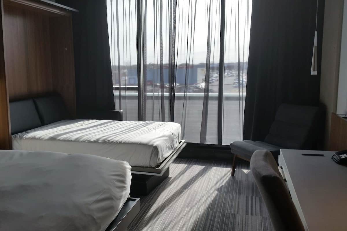 A hotel room with two beds, a desk, and a chair.