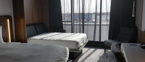 A hotel room with two beds, a desk, and a chair.