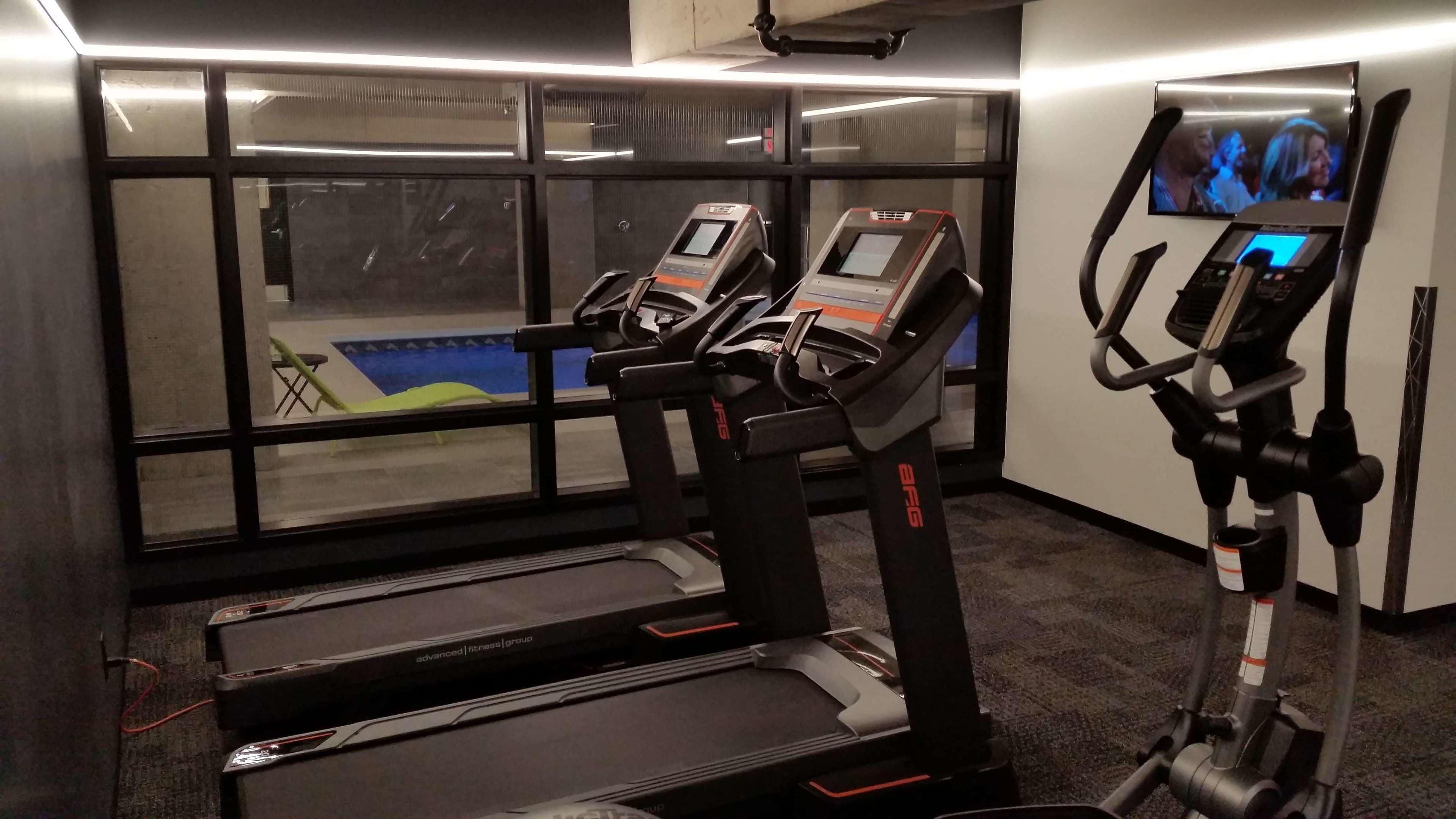 Un gimnasio con cintas de correr, una bicicleta estática y una pantalla de televisión.