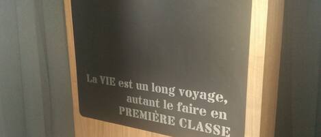 Un letrero con el texto "La VIE est un long voyage, autant le faire en PREMIÈRE CLASSE" sobre un fondo oscuro.