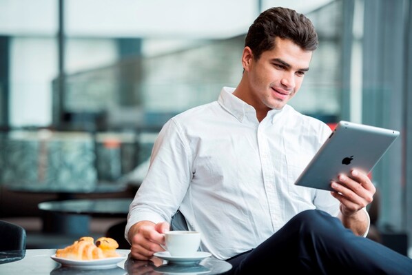 A person sitting at a table with a tablet and a cup of coffee, with croissants on the table. - Holiday Inn Express New Delhi International Airport T3 by IHG (New Delhi)