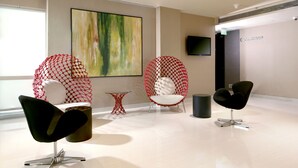 A modern interior with a large abstract painting, a black chair, a red netted chair, and a small table. - Holiday Inn Express New Delhi International Airport T3 by IHG (New Delhi)