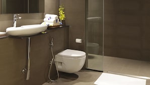 Un baño moderno con un espejo grande, un lavabo blanco, un inodoro y una cabina de ducha de vidrio.
