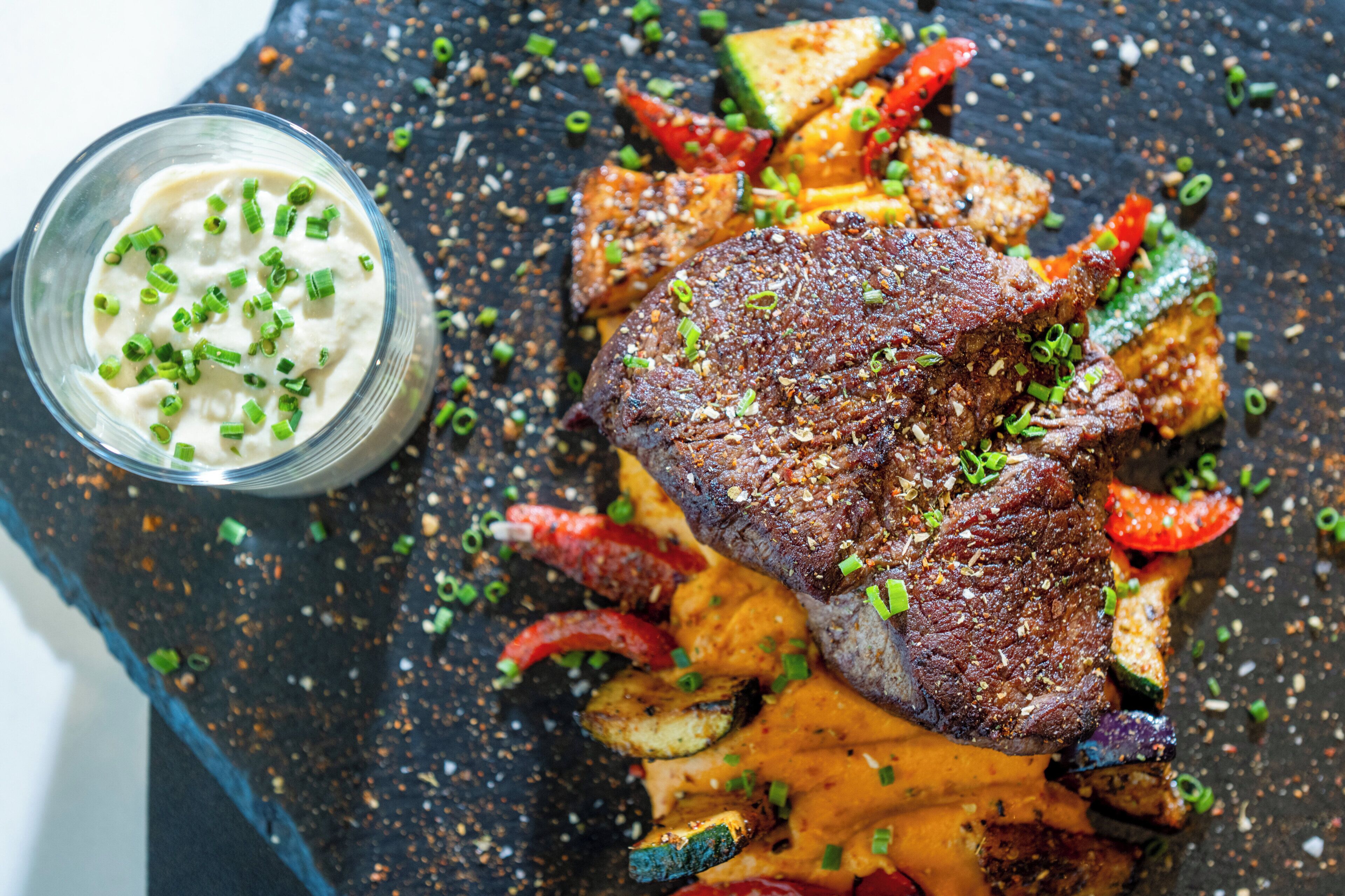 Un plato de carne con verduras y salsa.