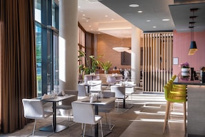 Um hall de hotel moderno com balcão de recepção, área de estar e grandes janelas.