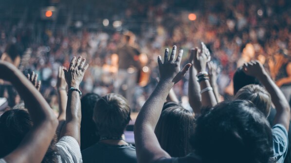 A crowded event with people raising their hands, likely at a concert or public gathering.