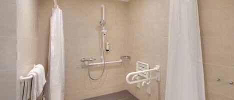 Un baño moderno con ducha, barras de apoyo y un perchero para toallas.