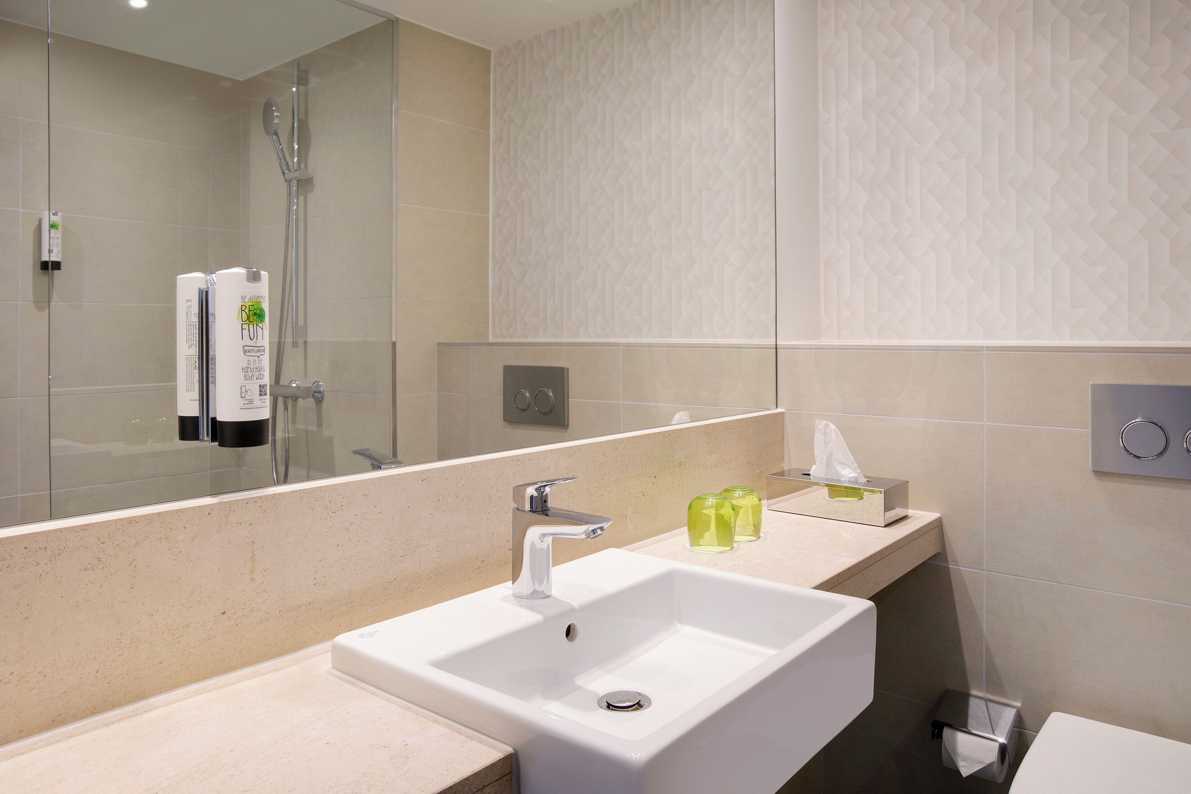 Un baño moderno con un espejo grande, un lavamanos blanco y una zona de ducha.