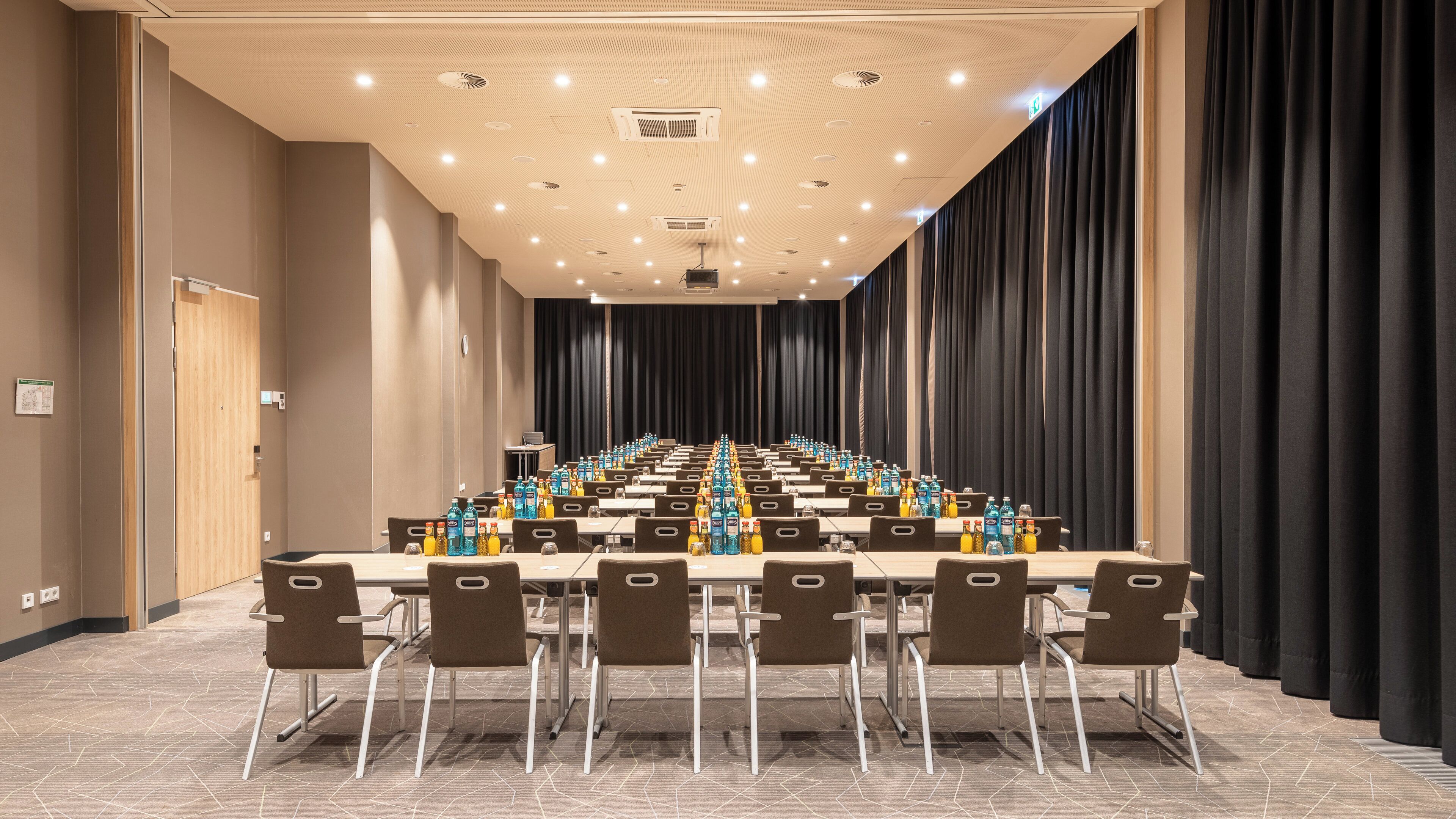 Un salón de conferencias con una larga mesa, sillas y bebidas embotelladas.