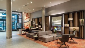A modern lobby with a sectional sofa, a small round table, and a seating area with chairs.