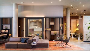 A modern lobby with a sectional sofa, a small table, and a seating area with chairs.