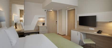 A modern hotel room with a large bed, a desk, a television, and a small chair.
