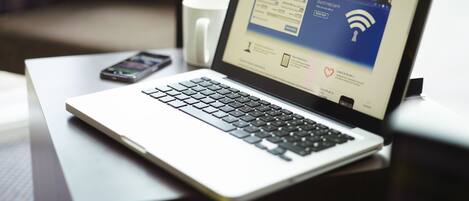 Una laptop sobre un escritorio con una taza de café cerca.